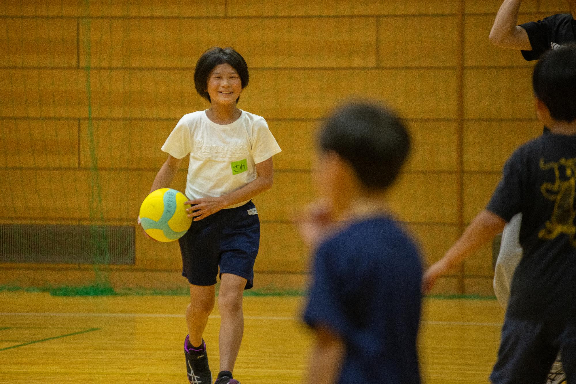 笑顔でバレーボールを持つ女の子の写真