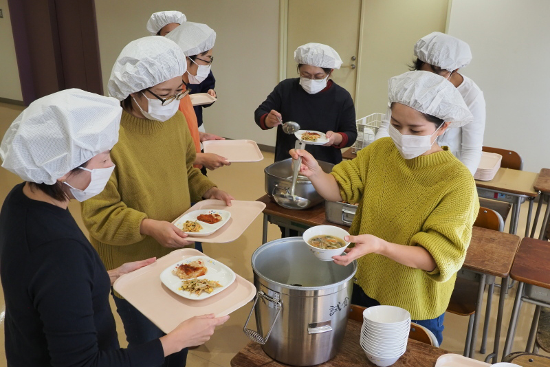 給食を鍋から器によそう参加者の写真