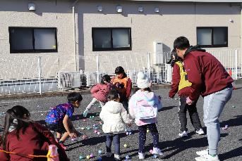 地面に散らばったボールを拾う子どもたちの写真