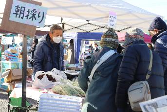 野菜を販売するお店に来場者が集まっている写真