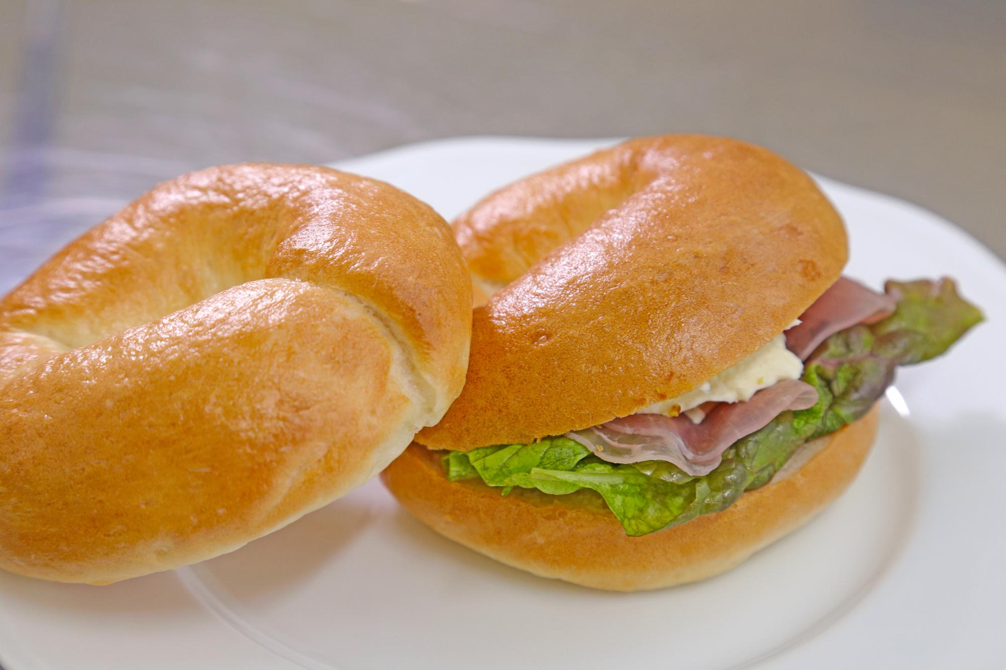 ハムとレタスが挟まれたベーグルの写真