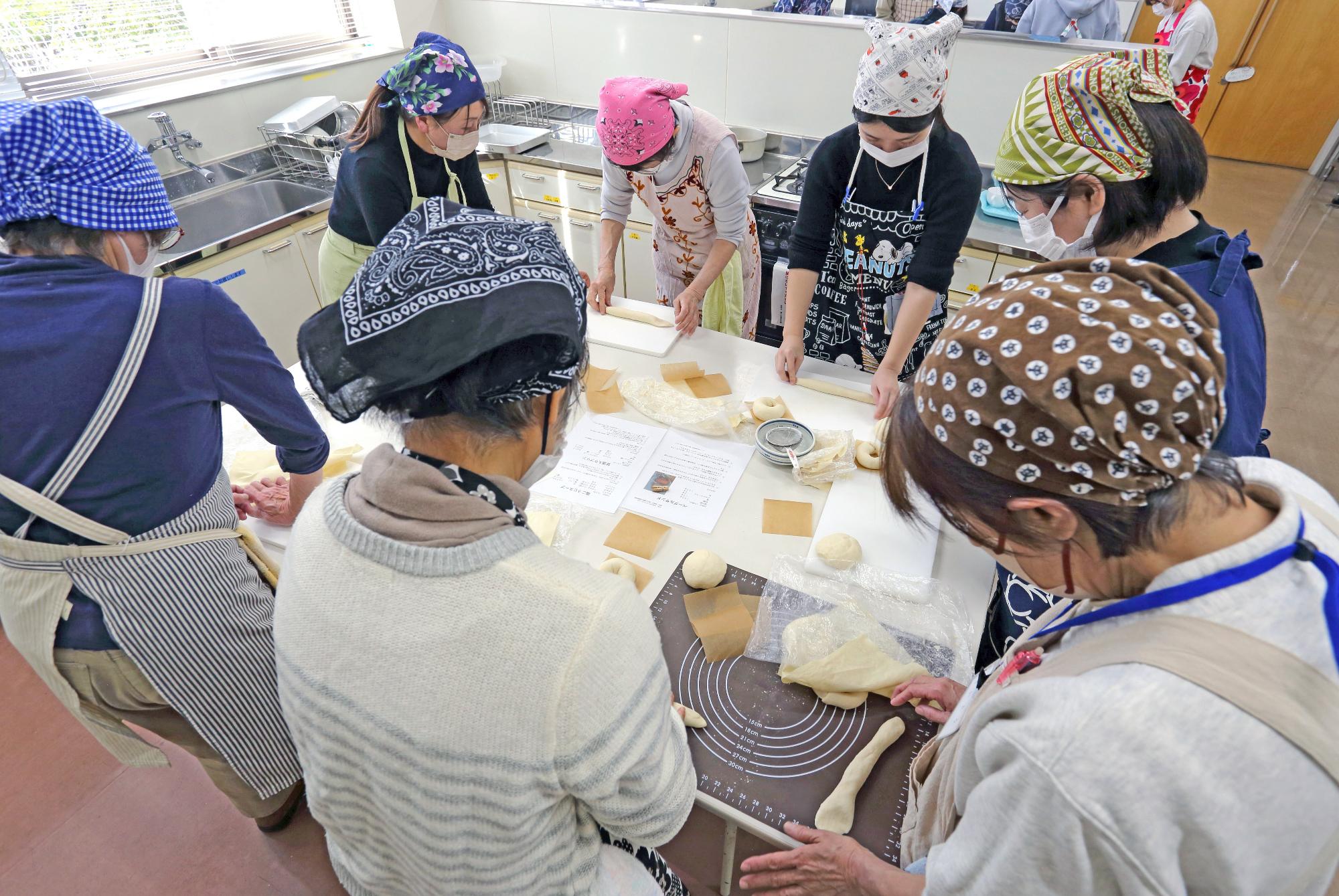 参加者たちが生地をこねてベーグルを作っている様子の写真