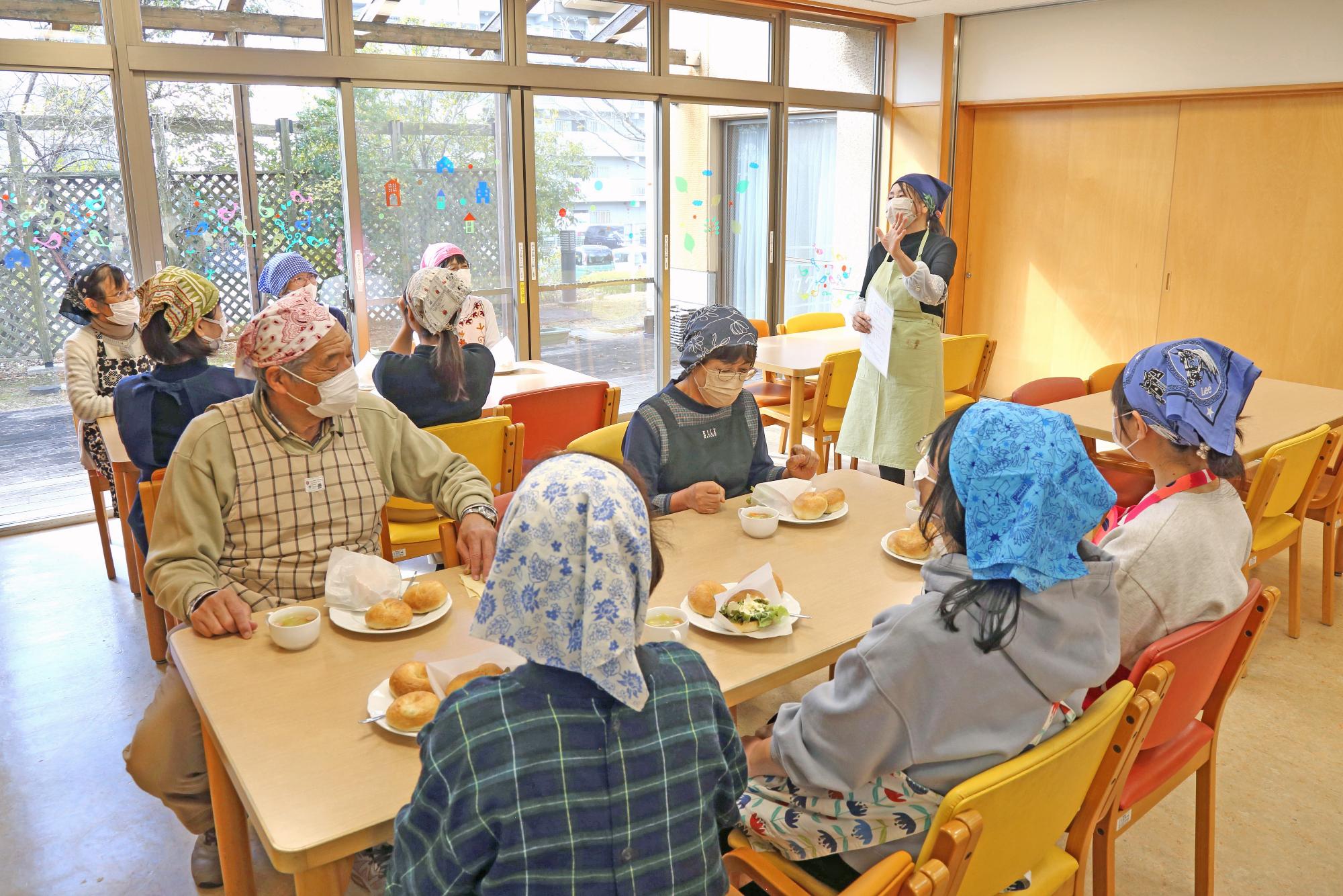 参加者たちが机を囲んで出来上がったベーグルを食べる写真