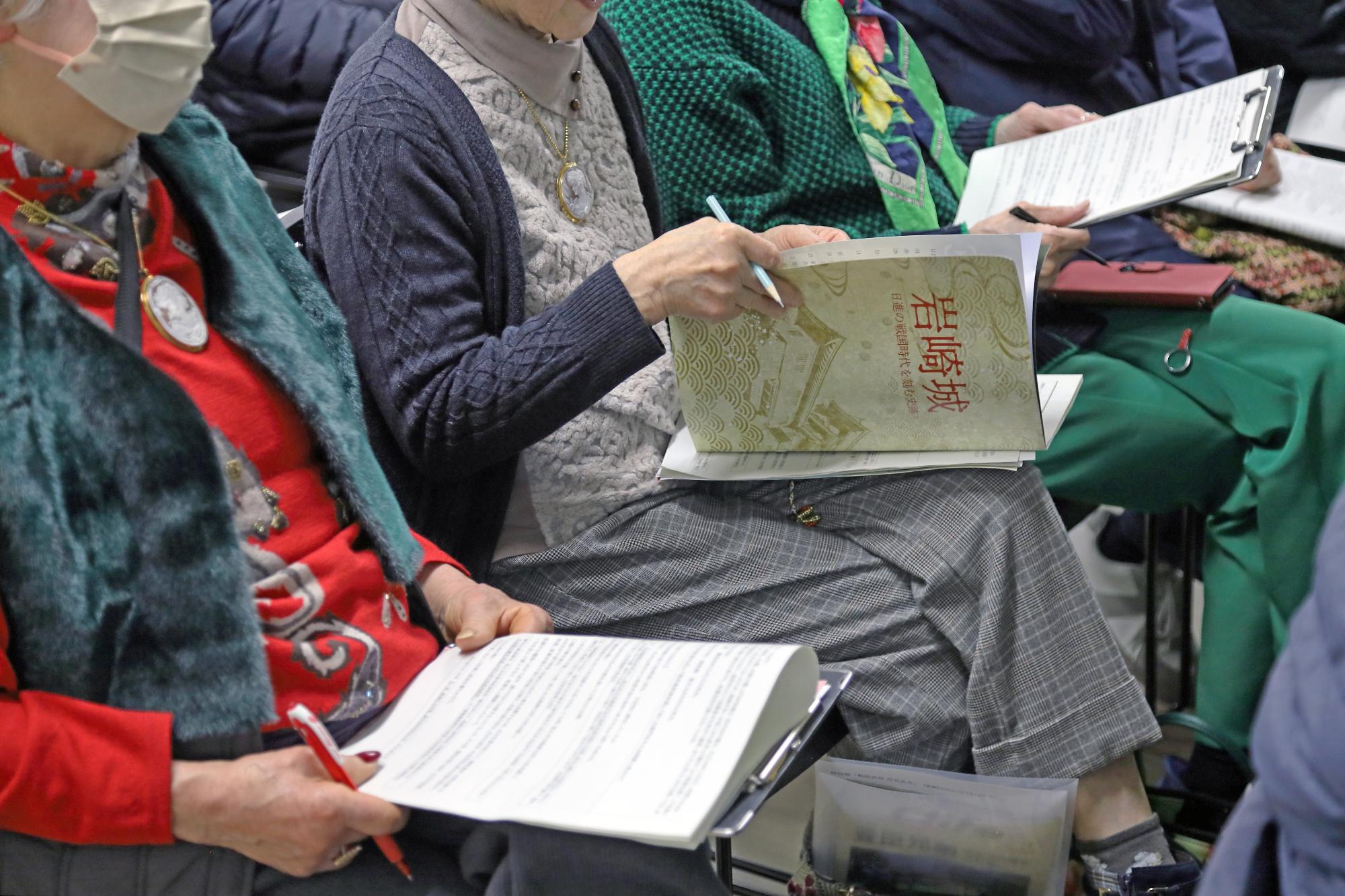 講演を聞く参加者たちが資料やノートにメモ書きを行う手元の写真