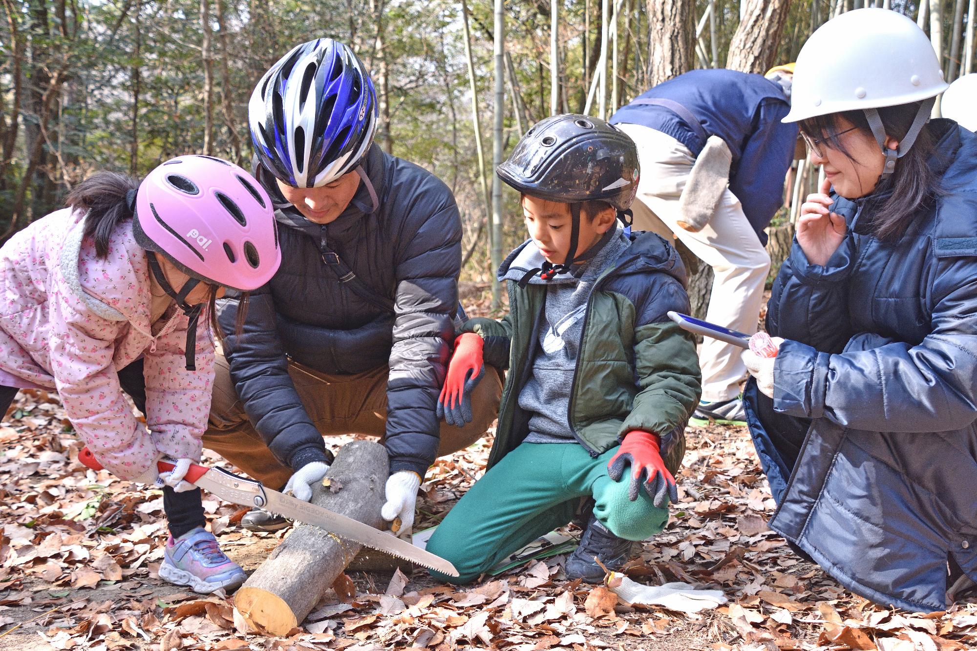 のこぎりで木を切る参加者のこどもたちの写真