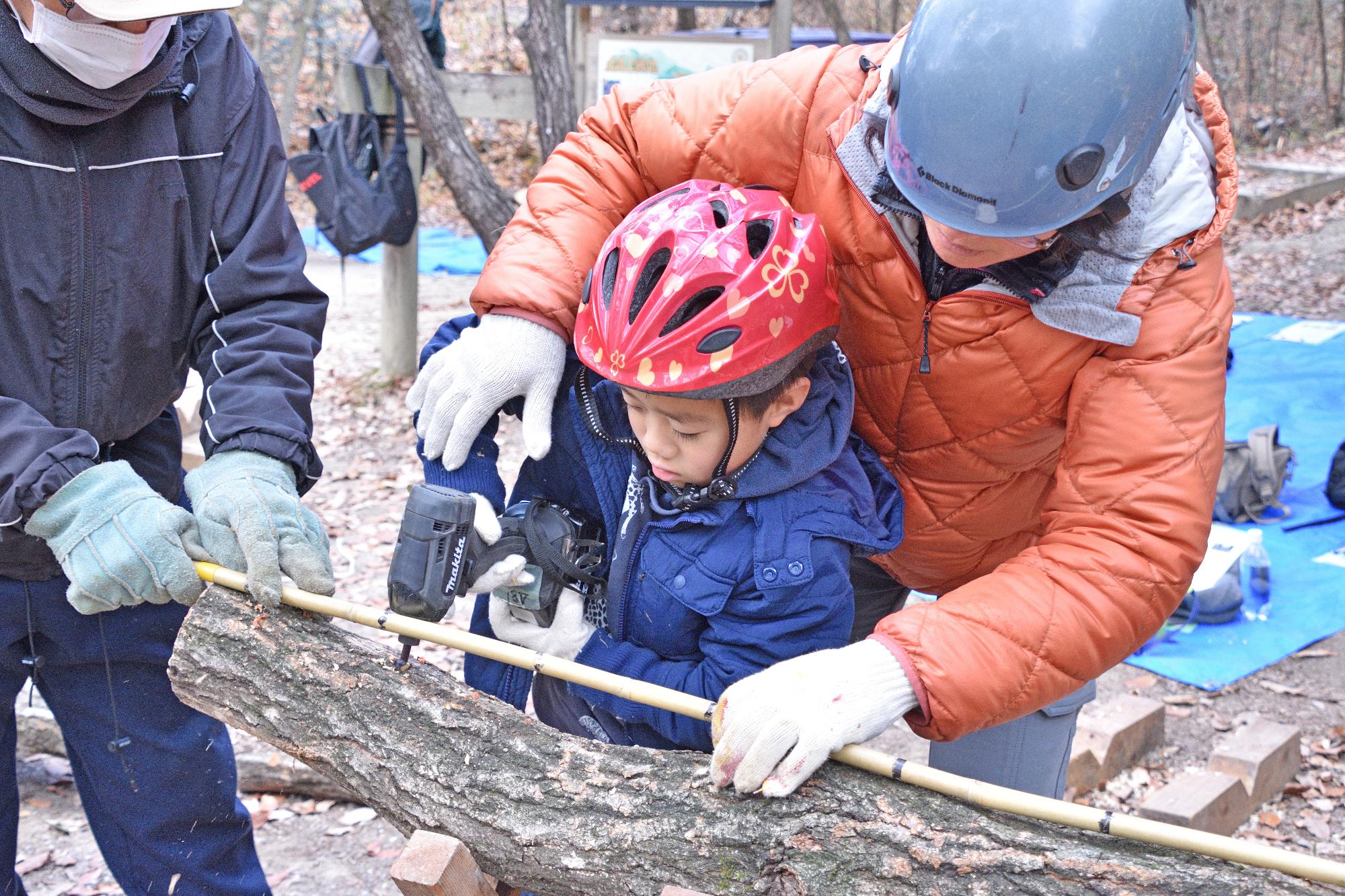 ドリルで原木の木に穴をあける参加者のこどもの写真