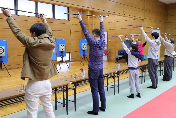 吹き矢の筒を頭上に上げる参加者の写真