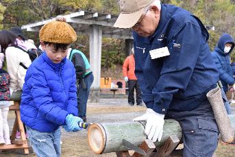 子どもの参加者がタケをのこぎりで切っている写真