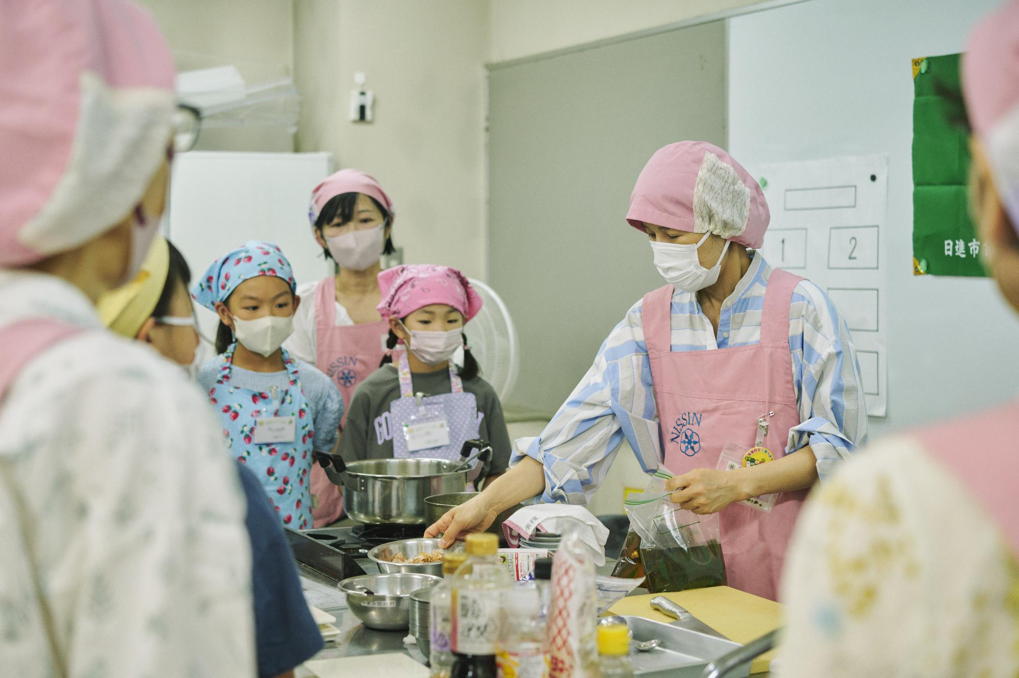 参加者に囲まれながら講師が料理の解説を行う写真