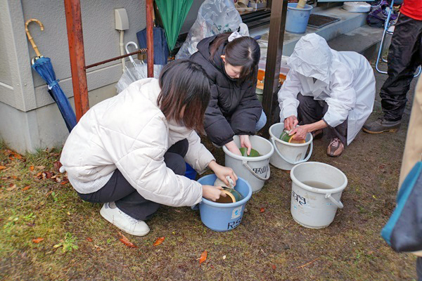 バケツの中で竹を洗う参加者の写真