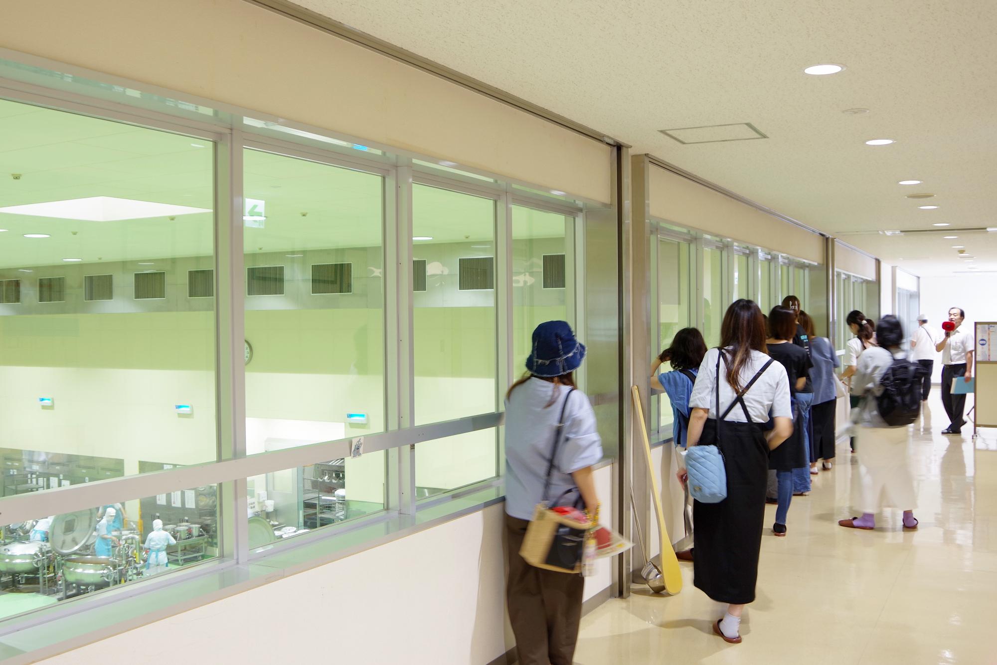 2階見学通路から調理室をのぞく参加者の様子の写真