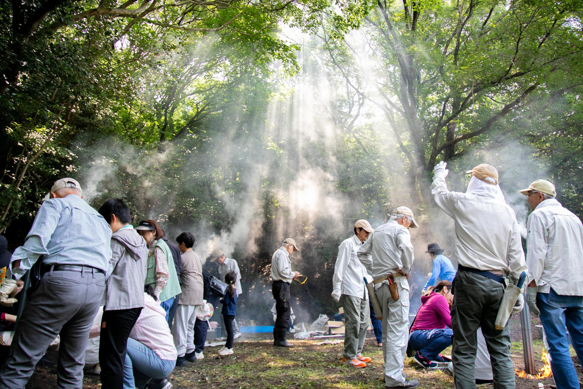 森の中で参加者たちが竹を燃やし煙が上がっている写真