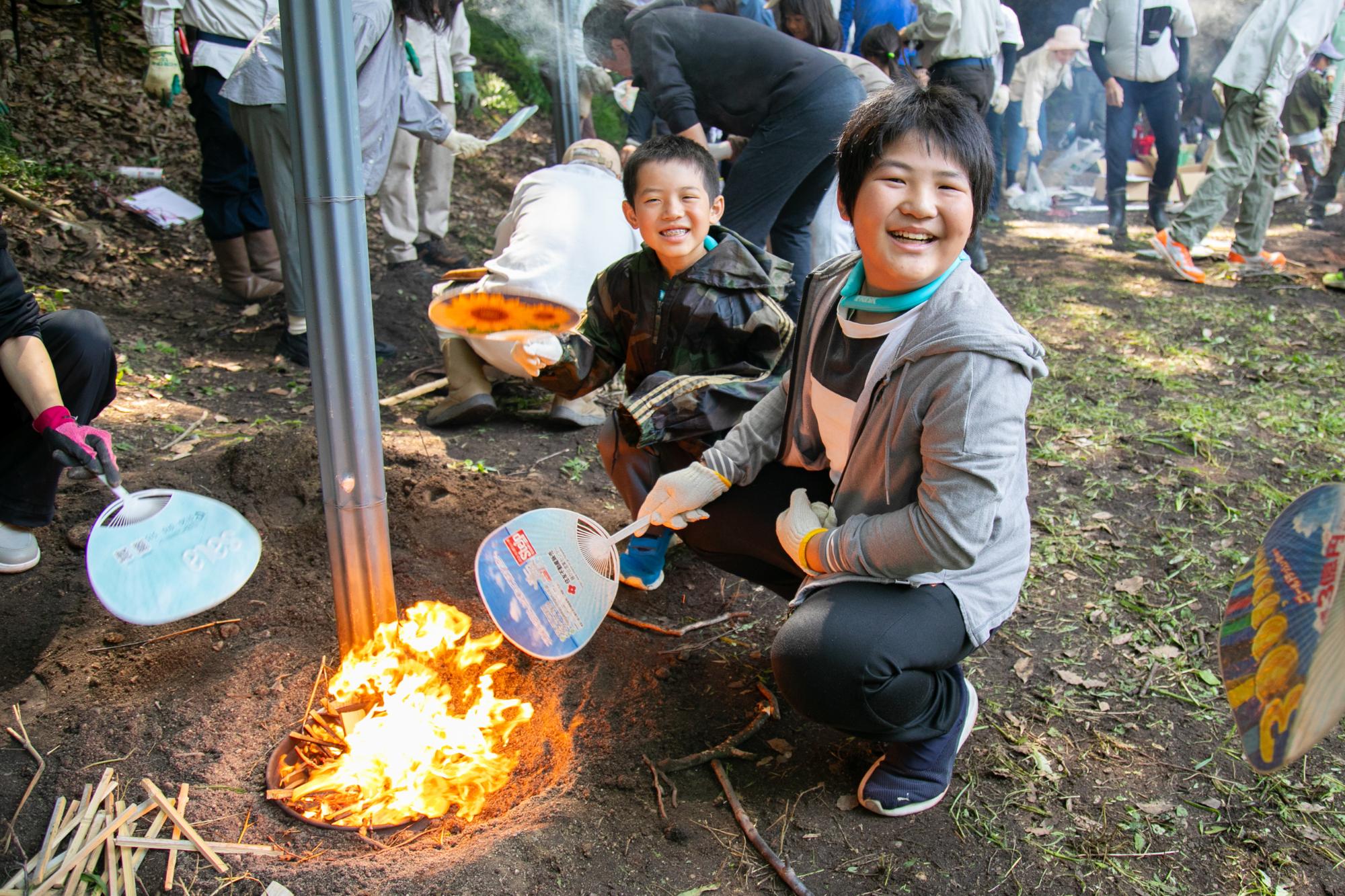 参加者のこどもたちがうちわであおいで火を起こす写真