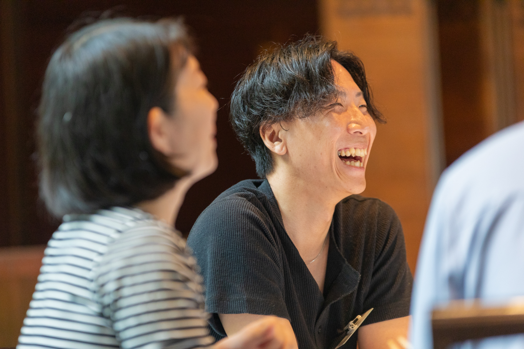 参加者が銘々にテーブルを囲んで椅子に座りながら談笑している写真