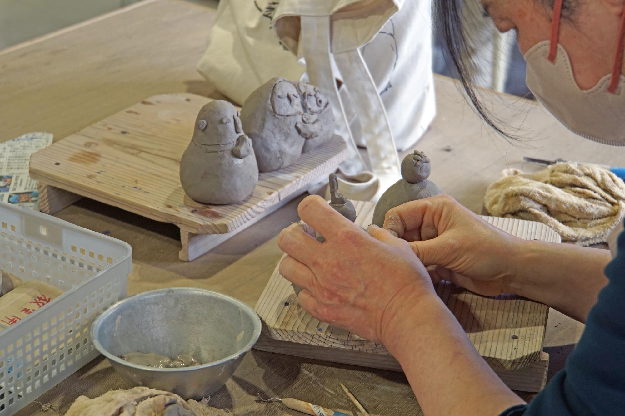 真剣なまなざしで粘土から自身の作品を作っている様子の写真