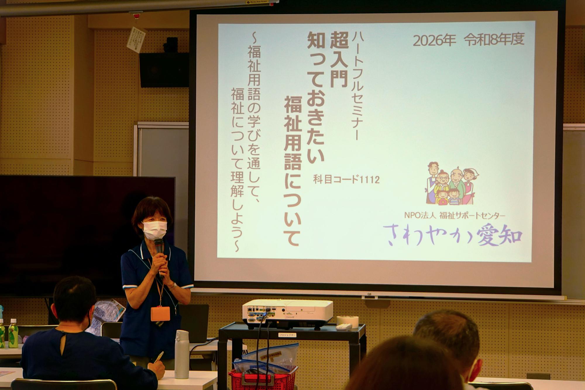 マイクを持ってスライドを解説する講師の写真
