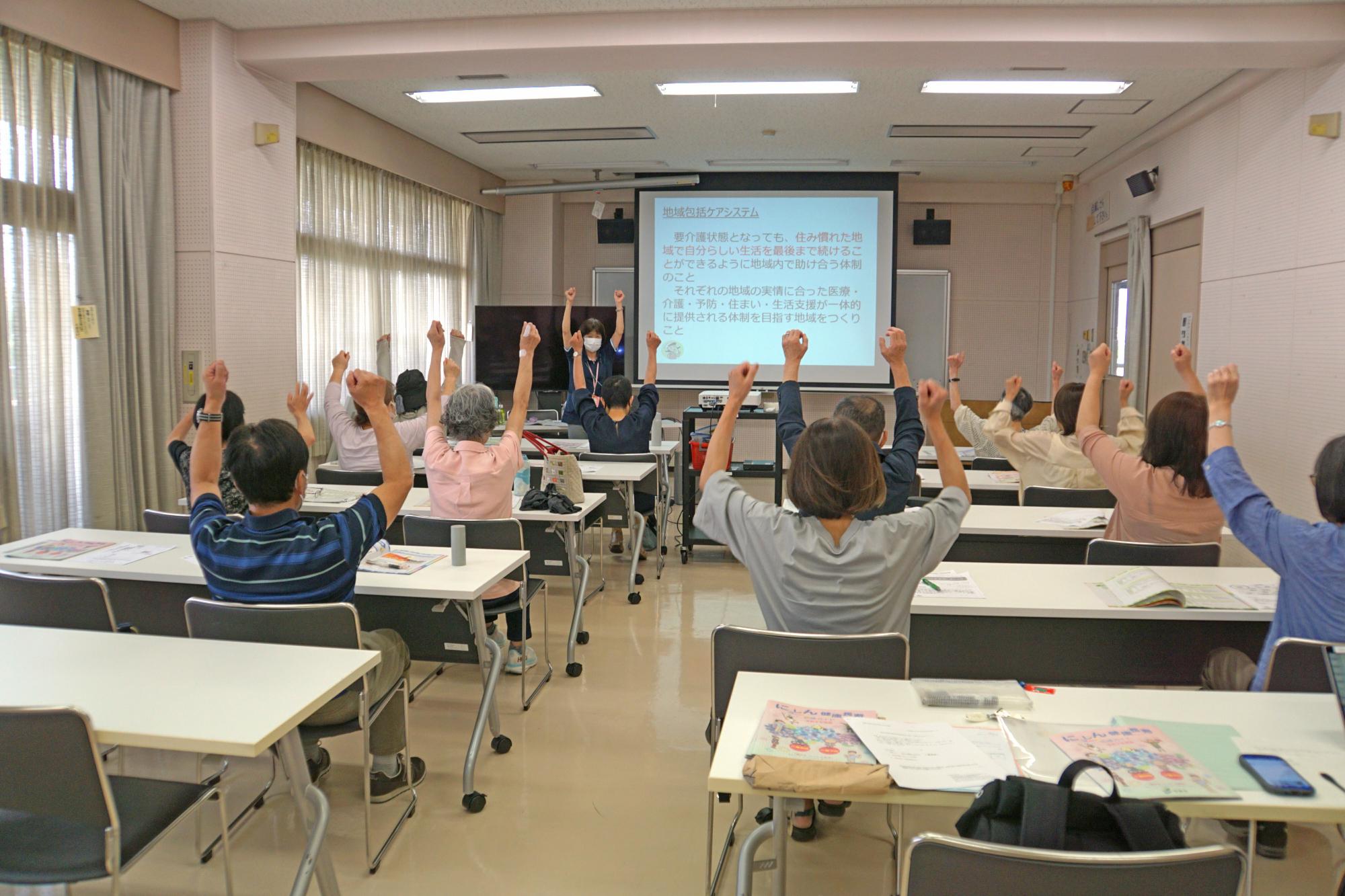 腕を上げて体操を行う参加者たちの写真