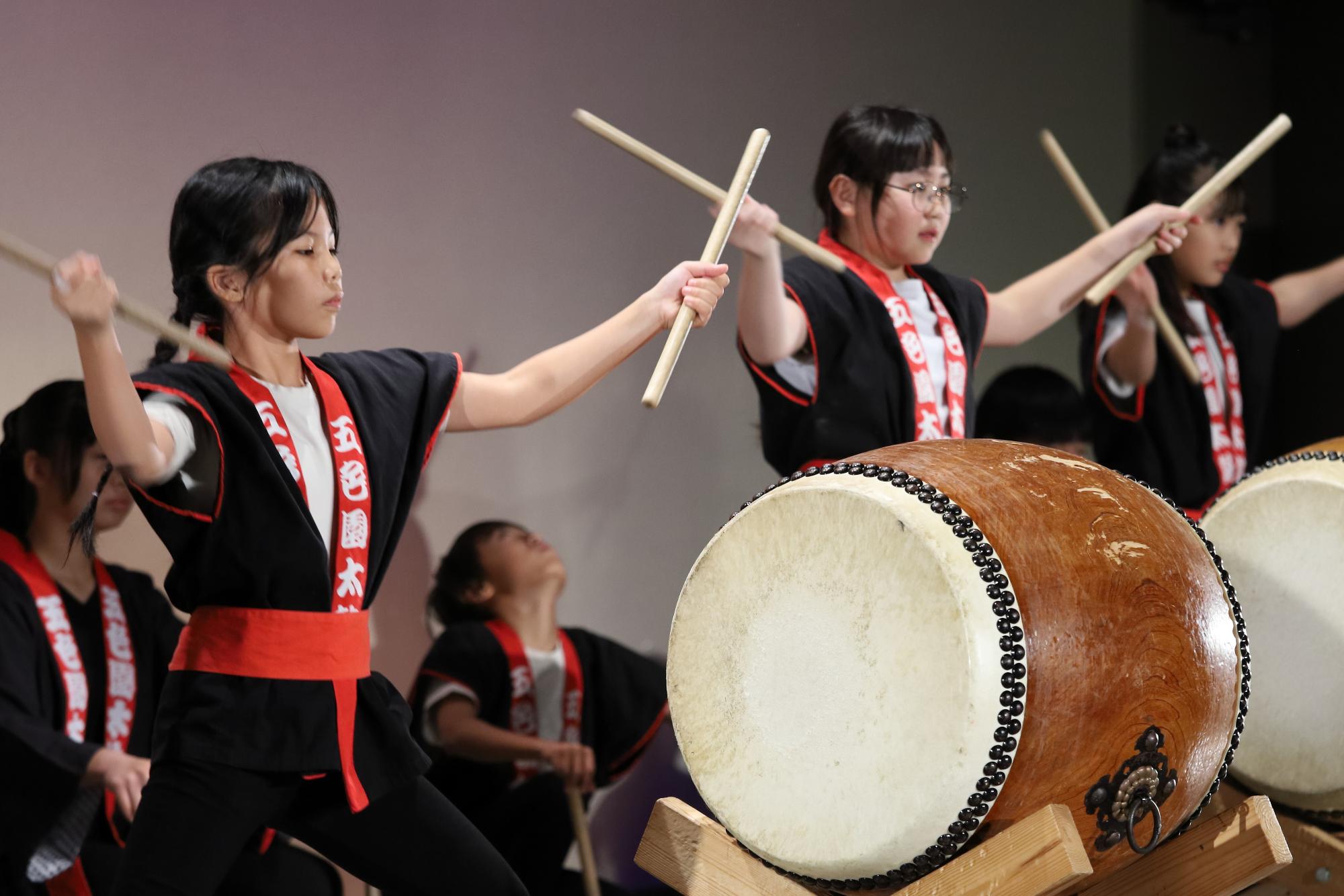 ステージ上で太鼓の演奏を披露するこどもたちの写真