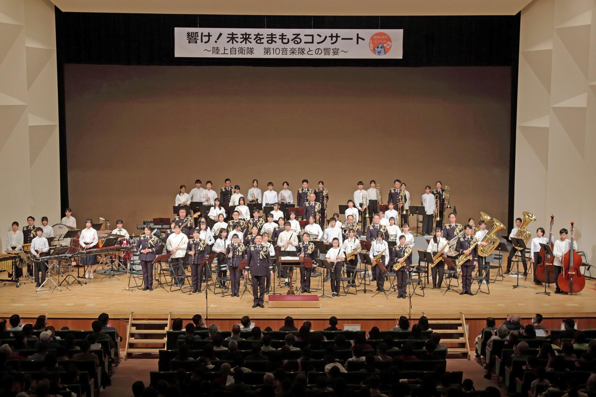 演奏終了後に全員起立して礼を行う音楽隊の写真