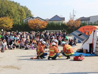消防・自衛隊による倒壊した家屋からの人命救助を想定した訓練の様子とそれを熱心に見る参加者の写真