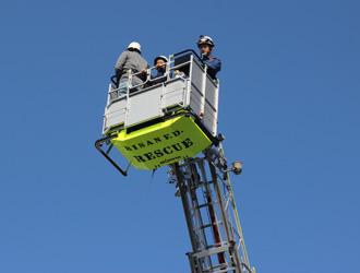 ヘルメットを被った参加者がはしご車の試乗体験をしている様子の写真