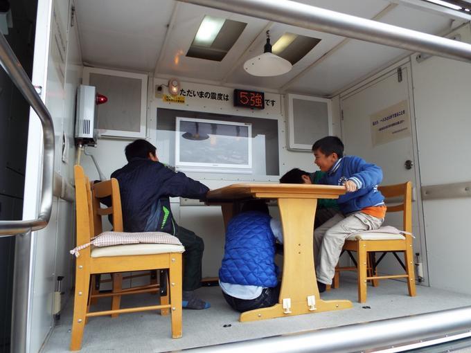 地震体験車「なまず号」で地震体験をする参加者の写真