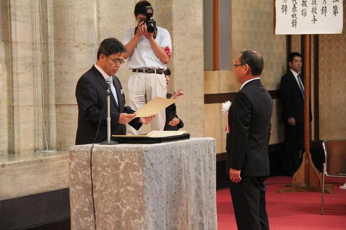 表彰式にて大村愛知県知事より表彰状を受け取る横井さんの写真