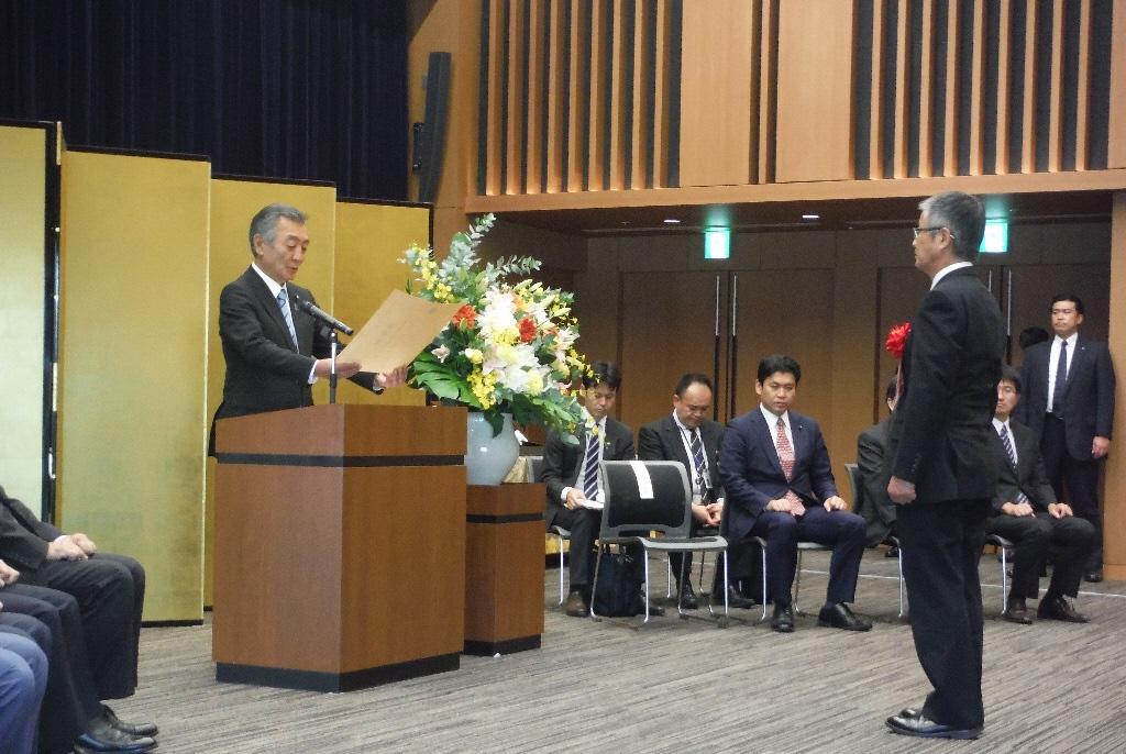 表彰式にて松本内閣府特命担当大臣より表彰を受ける日東東山自主防災会会長の鈴木さんの写真