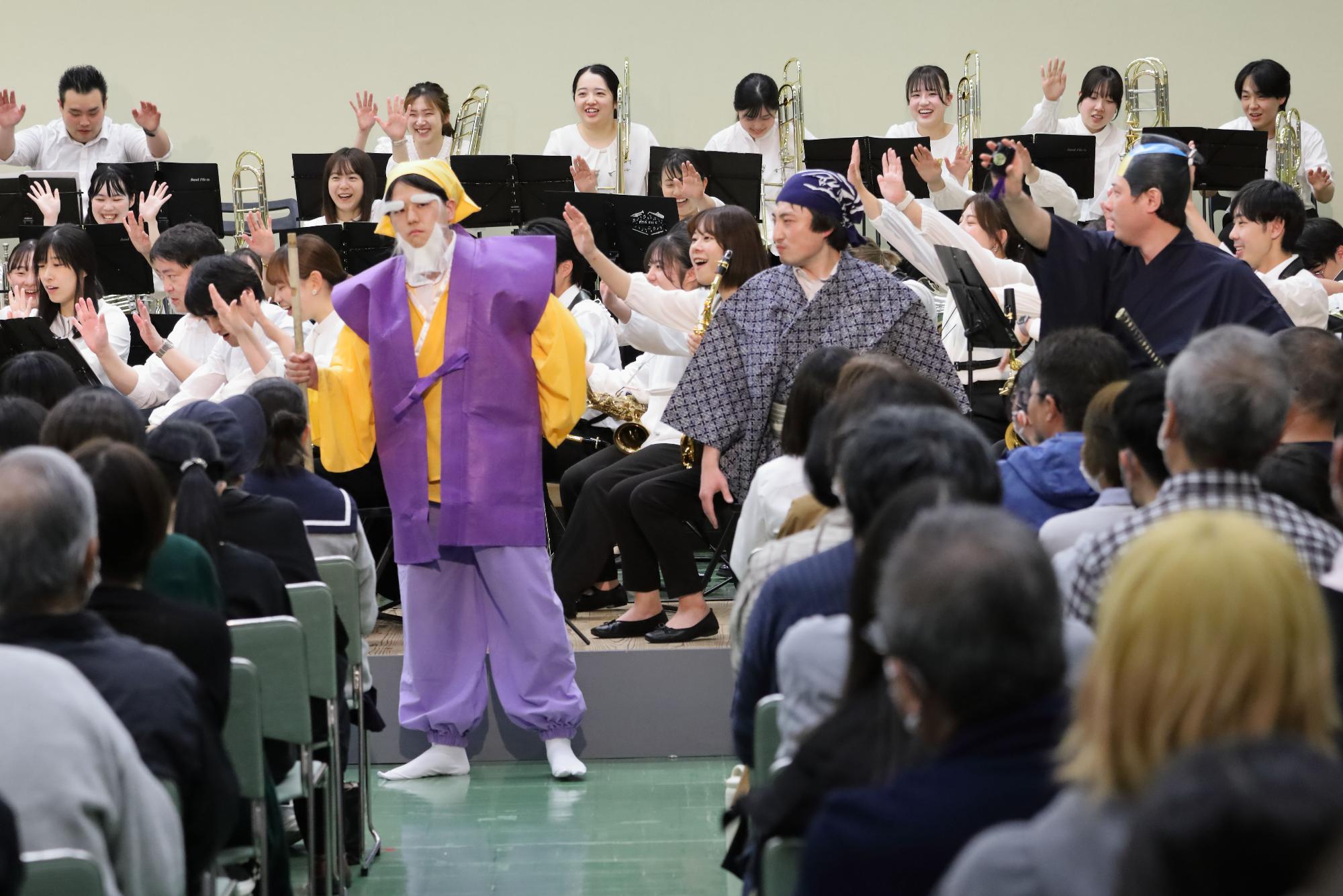 にこやかな表情で時代劇メドレーを演奏する団員とそれに参加する観客の写真