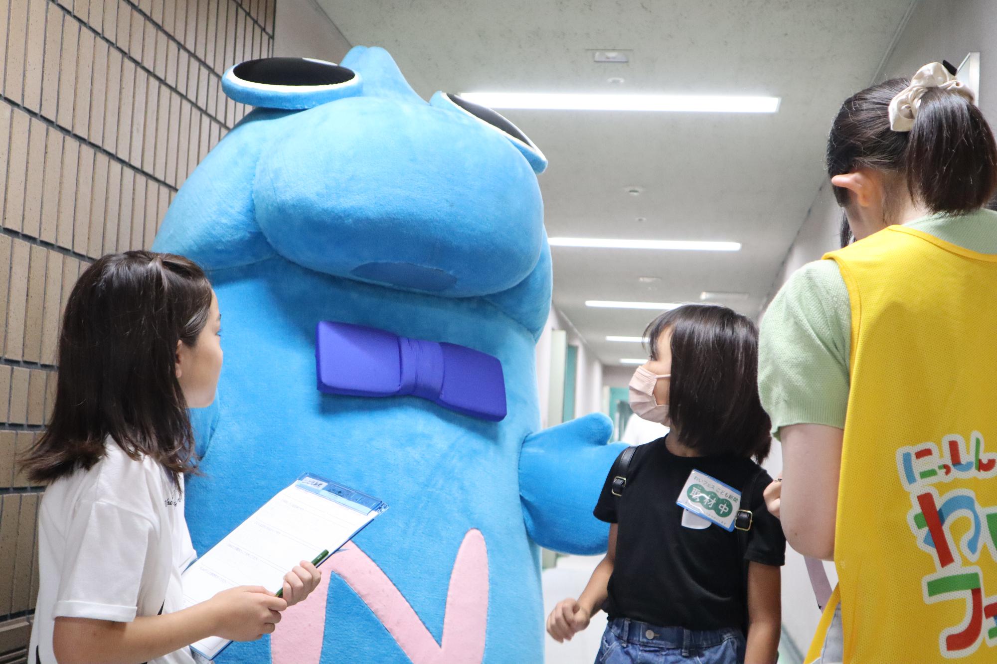 子ども新聞の記者と会場をまわるニッシーの写真