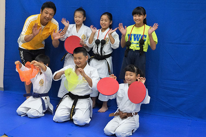 「配信される動画を見てください」とアピールするモデル役の小学生と長谷川トレーナー