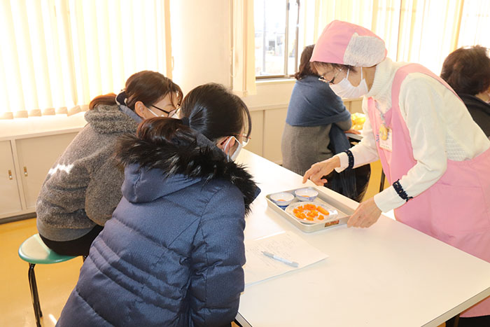 ペースト状と手づかみ食べ用のニンジンのサンプルを眺める受講者たち