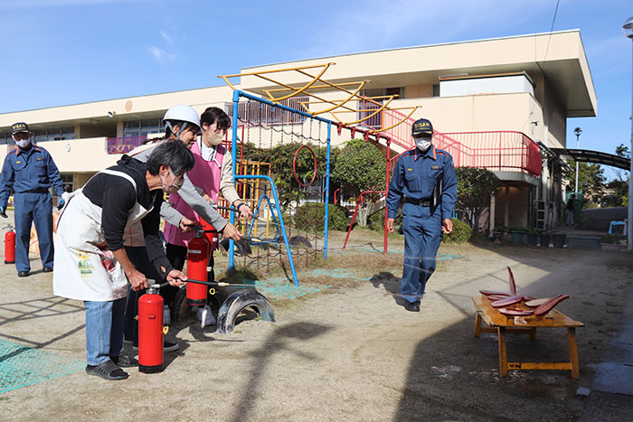 水消火器を手に消火訓練をする保育士たち