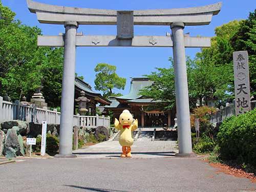 天地社の石の鳥居の下で、ポーズをとるへルピーの写真前にて