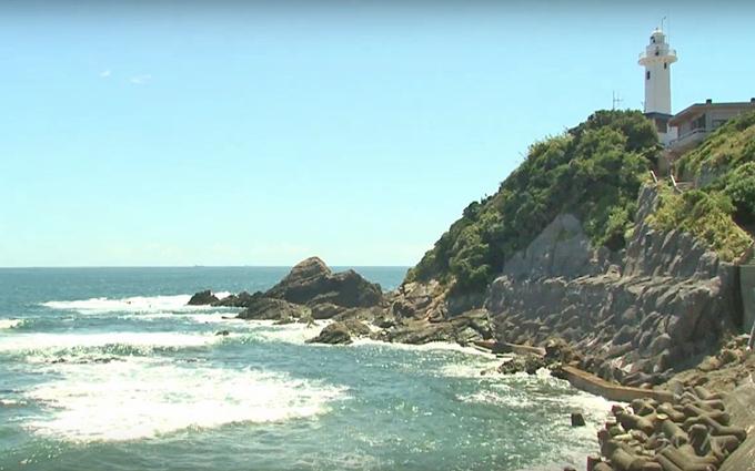 崖に立っている灯台と海の風景写真