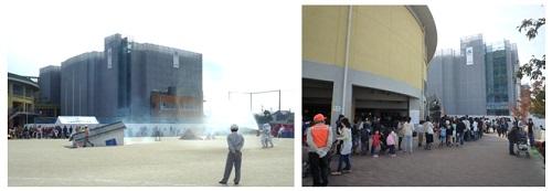 地域防災訓練にて、建物に消火器を噴射している様子を少し離れたところから撮影した写真、建物のまわりに集まる参加者の写真